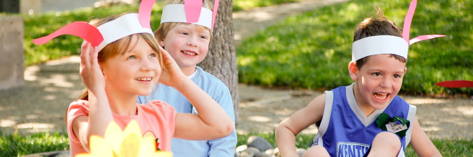 Children with happy smiles on their faces, they all have a band of paper around their heads with pink paper bunny ears.