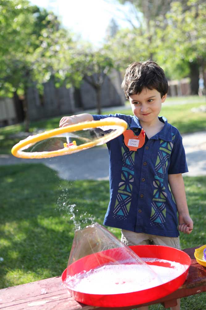 A boy using a big bubble maker.
