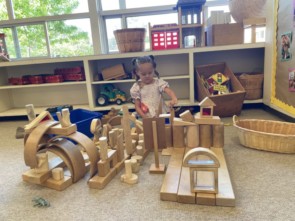 a child playing with wooden blocks, building a little city